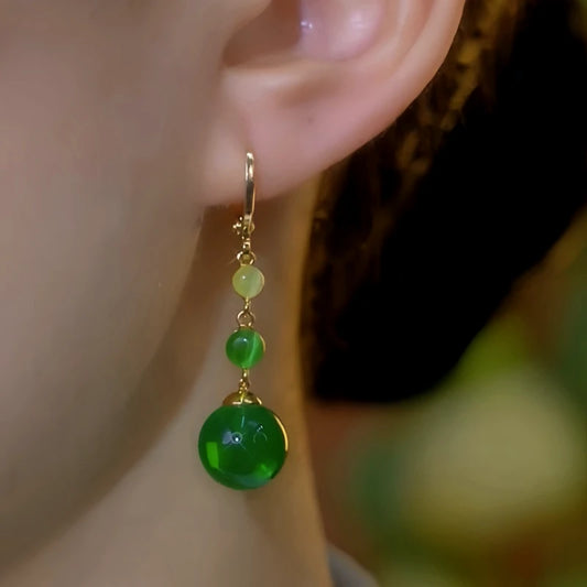 Model showcasing the dangle and style of the 14K Gold-Plated Elegant Green Bead Tassel Earrings