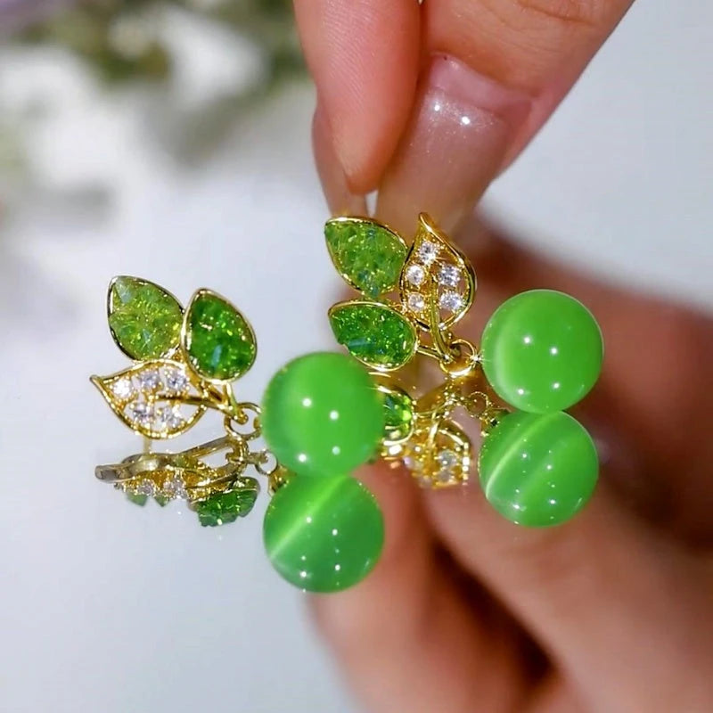 Model showcasing the dangle and style of the 14K Gold-Plated Elegant Green Diamond Leaf Bead Earrings