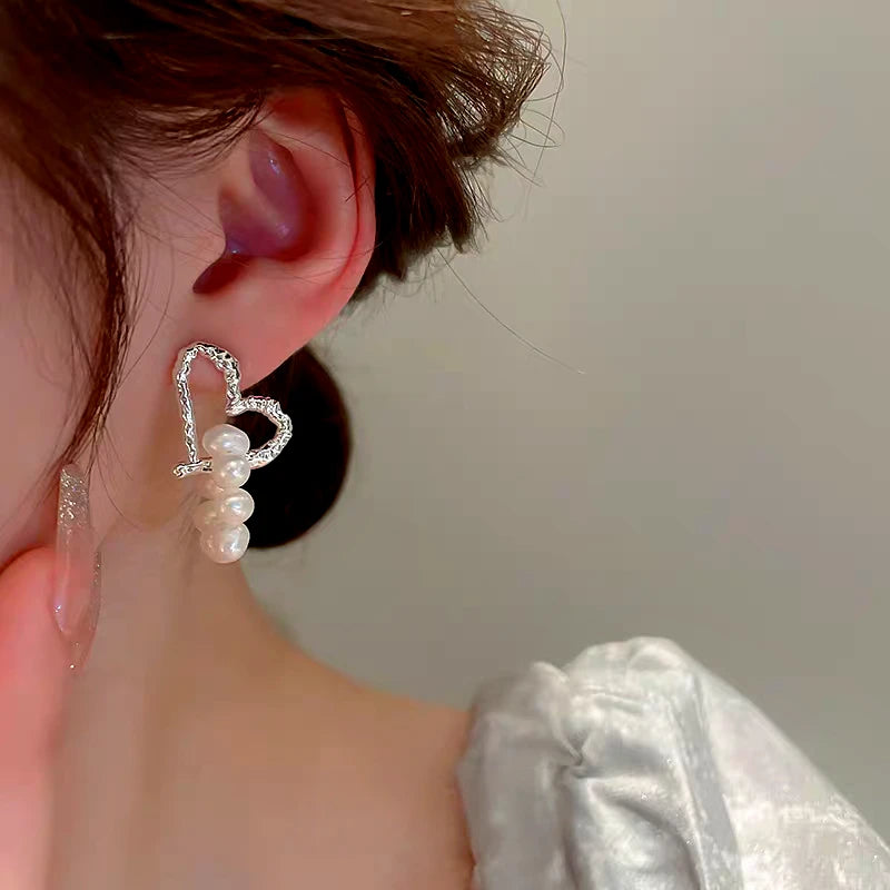 Model showcasing the dangle and style of the 14K Gold-Plated Elegant Heart Pearl Tassel Earrings