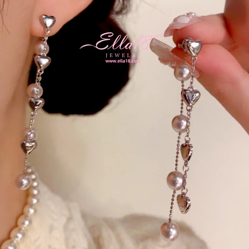 Model showcasing the dangle and style of the 14K Gold-Plated Elegant Heart Pearl Tassel Earrings