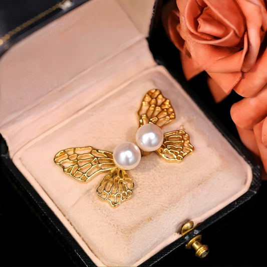 Model showcasing the dangle and style of the 14K Gold-Plated Elegant Hollow Pearl Butterfly Earrings