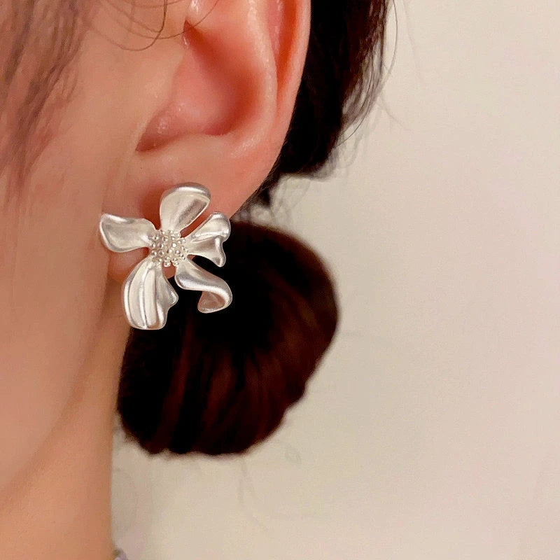 Model showcasing the dangle and style of the 14K Gold-Plated Elegant Irregular Flower Stud Earrings