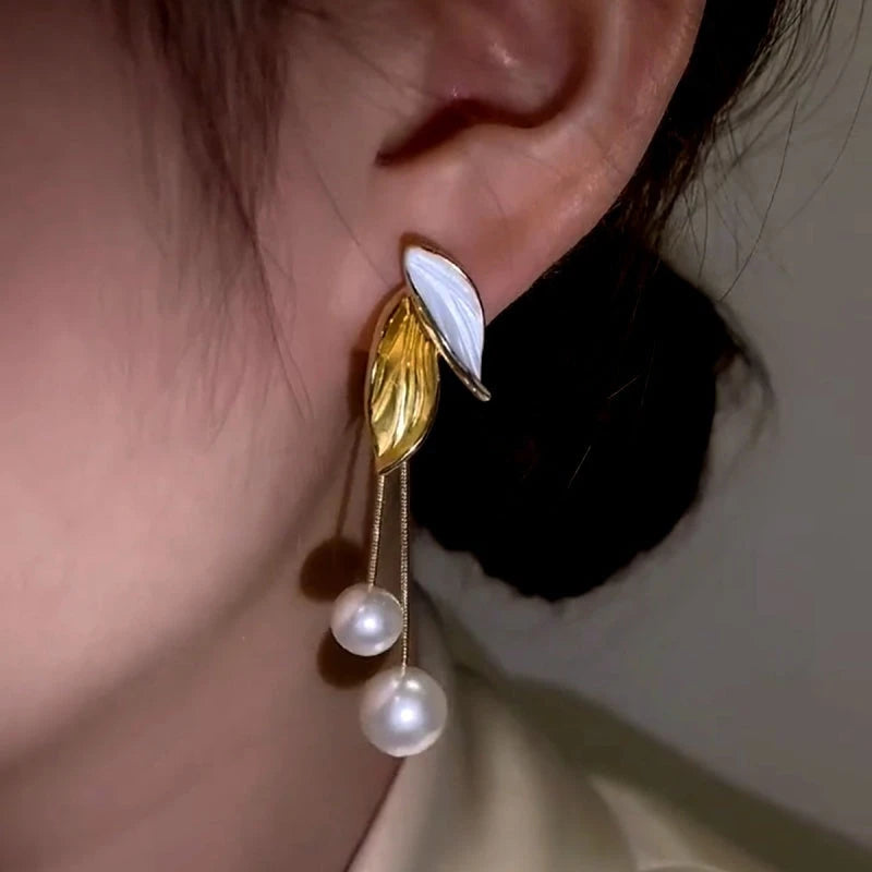 Model showcasing the dangle and style of the 14K Gold-Plated Elegant Leaf Pearl Tassel Earrings