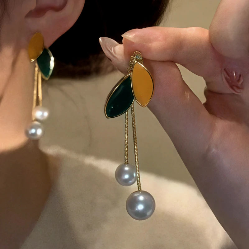 Model showcasing the dangle and style of the 14K Gold-Plated Elegant Leaf Pearl Tassel Earrings