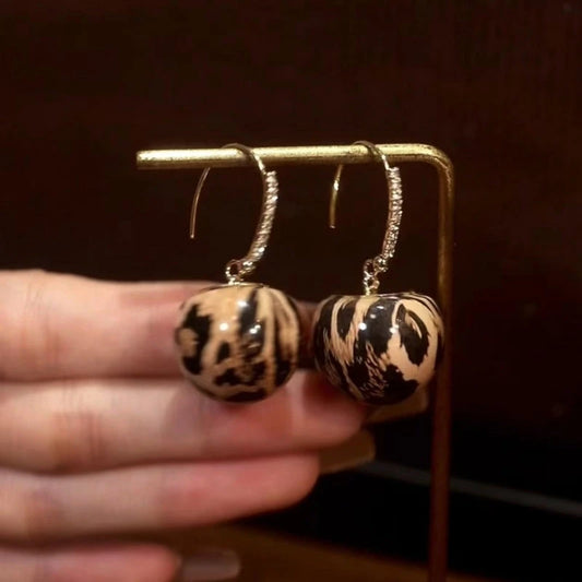 Model showcasing the dangle and style of the 14K Gold-Plated Elegant Leopard Print Ball Ear Hooks