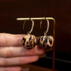 Model showcasing the dangle and style of the 14K Gold-Plated Elegant Leopard Print Ball Ear Hooks