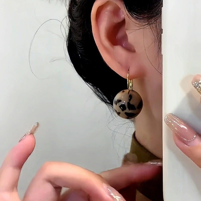 Model showcasing the dangle and style of the 14K Gold-Plated Elegant Leopard Print Ball Earrings