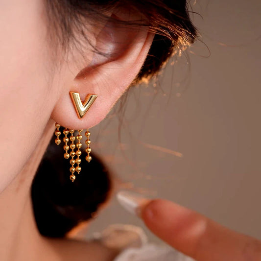 Model showcasing the dangle and style of the 14K Gold-Plated Elegant Letter V Tassel Earrings