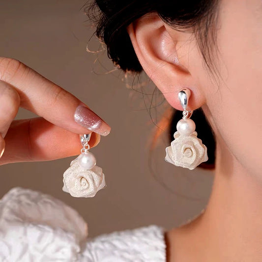 Model showcasing the dangle and style of the 14K Gold-Plated Elegant Mesh Rose Bead Cross Earrings