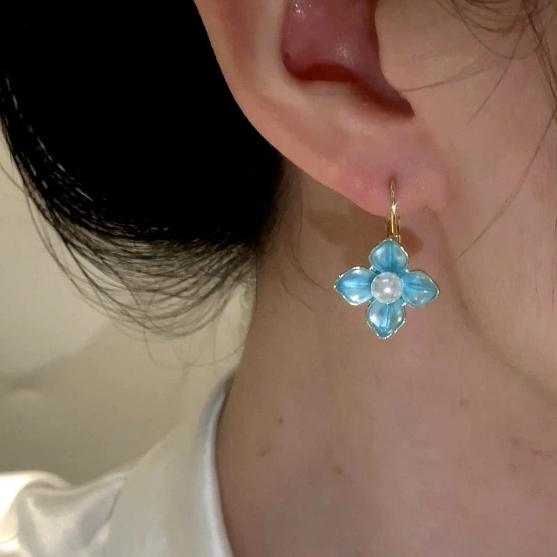 Model showcasing the dangle and style of the 14K Gold-Plated Elegant Oil Drop Pearl Blue Flower Earrings