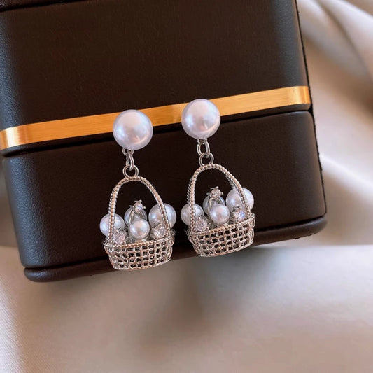 Model showcasing the dangle and style of the 14K Gold-Plated Elegant Pearl Basket Earrings