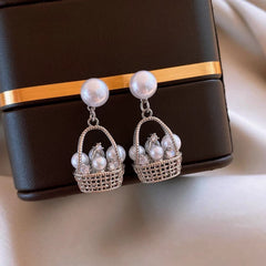 Model showcasing the dangle and style of the 14K Gold-Plated Elegant Pearl Basket Earrings