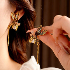 Angled view of the 14K Gold-Plated Elegant Pearl Dragonfly Tassel Earrings