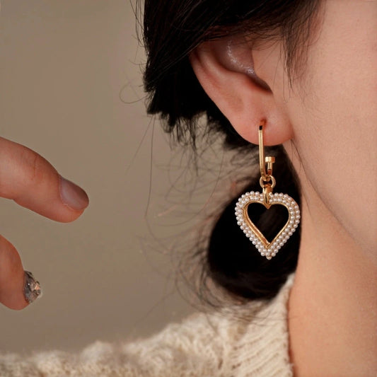 Model showcasing the dangle and style of the 14K Gold-Plated Elegant Pearl Heart Earrings
