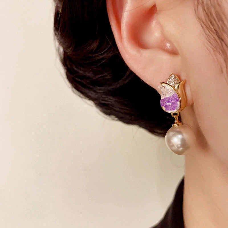Model showcasing the dangle and style of the 14K Gold-Plated Elegant Purple Crystal Tulip Pearl Earrings