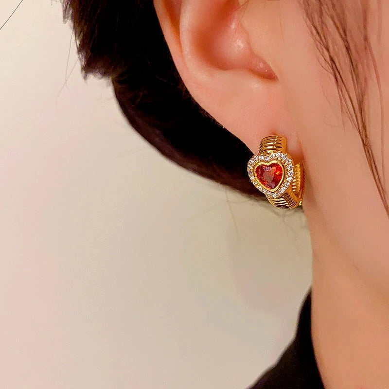 Model showcasing the dangle and style of the 14K Gold-Plated Elegant Red Heart Hoop Earrings