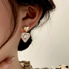 Model showcasing the dangle and style of the 14K Gold-Plated Elegant Rhinestone Heart Earrings