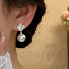 Model showcasing the dangle and style of the 14K Gold-Plated Elegant Shell Pearl Earrings