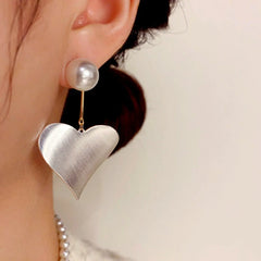 Model showcasing the dangle and style of the 14K Gold-Plated Elegant Simple Exaggerated Metal Heart Pearl Earrings