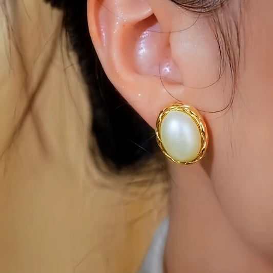 Model showcasing the dangle and style of the 14K Gold-Plated Elegant Textured Geometric Oval Pearl Stud Earrings