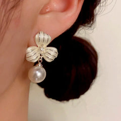 Model showcasing the dangle and style of the 14K Gold-Plated Elegant Thick Silver Clover Pearl Earrings
