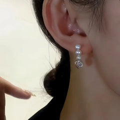 Model showcasing the dangle and style of the 14K Gold-Plated Elegant Three Pearl Zircon Heart Earrings