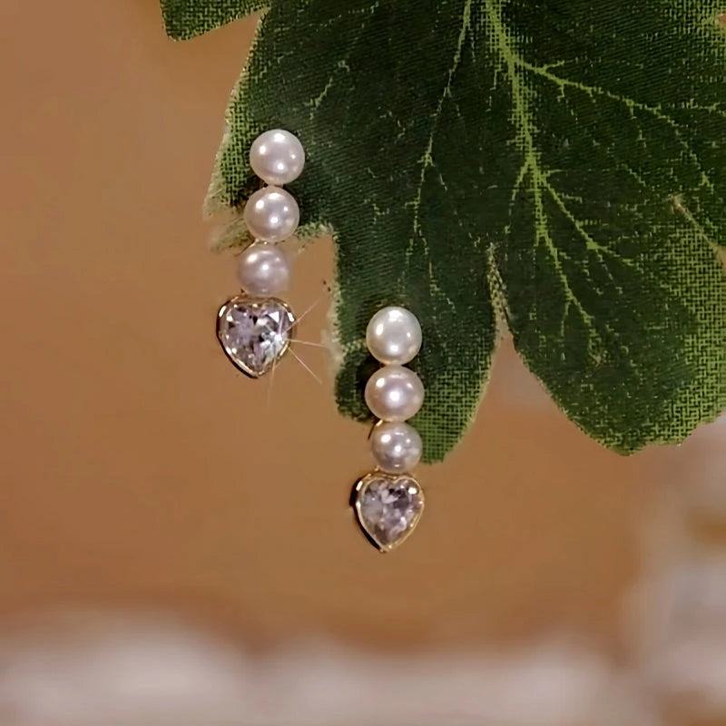 Angled view of the 14K Gold-Plated Elegant Three Pearl Zircon Heart Earrings