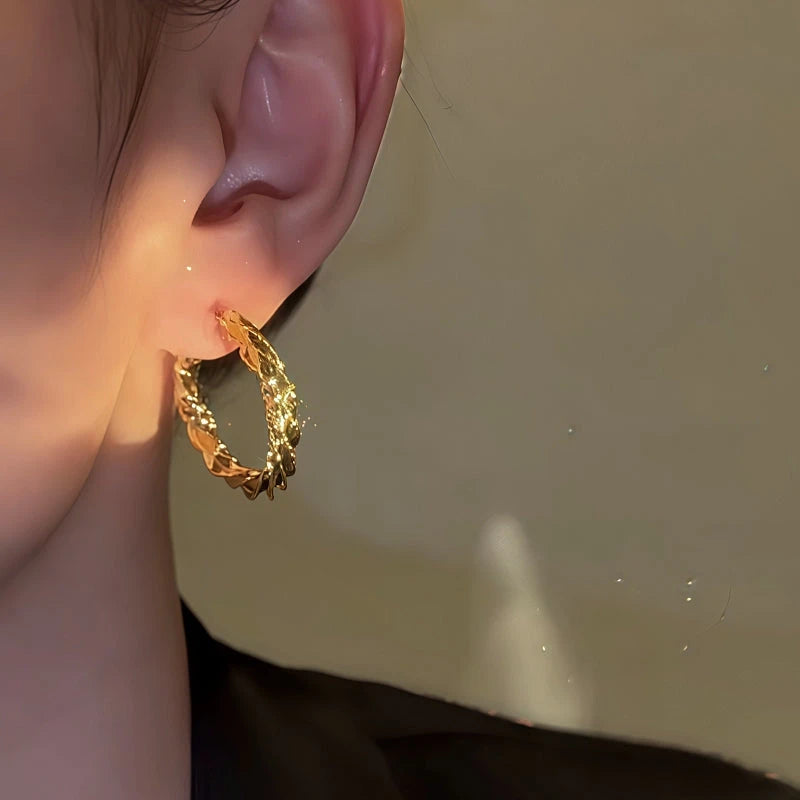 Model showcasing the dangle and style of the 14K Gold-Plated Elegant Twisted Hoop Earrings