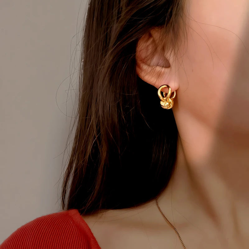 Model showcasing the dangle and style of the 14K Gold-Plated Elegant Twisted Knotted Earrings