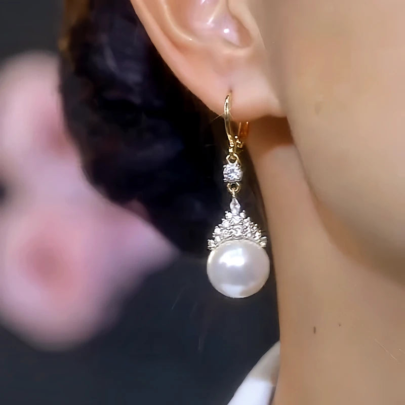 Model showcasing the dangle and style of the 14K Gold-Plated Elegant White Pearl Zircon Crown Earrings