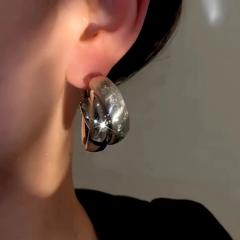 Model showcasing the dangle and style of the 14K Gold-Plated Elegant Wide Cross Hoop Earrings