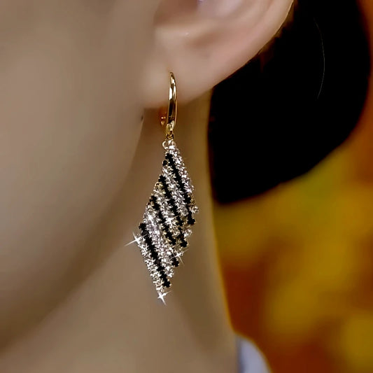 Model showcasing the dangle and style of the 14K Gold-Plated Elegant Zircon Black And White Earrings