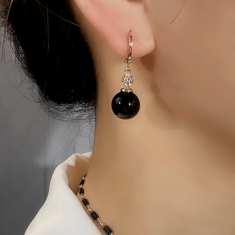 Model showcasing the dangle and style of the 14K Gold-Plated Elegant Zircon Black Bead Earrings