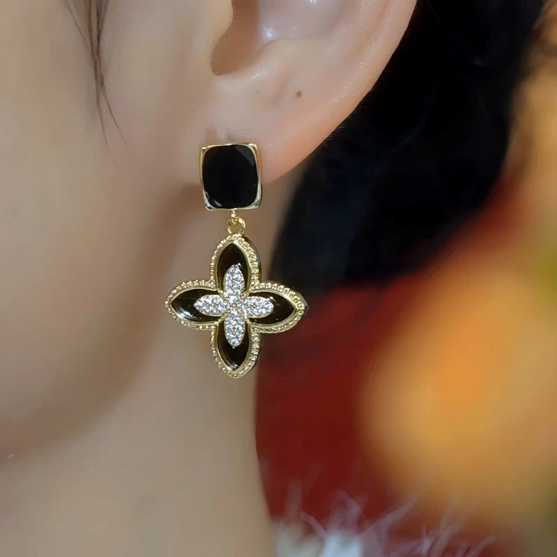 Model showcasing the dangle and style of the 14K Gold-Plated Elegant Zircon Black Four-Leaf Flower Earrings