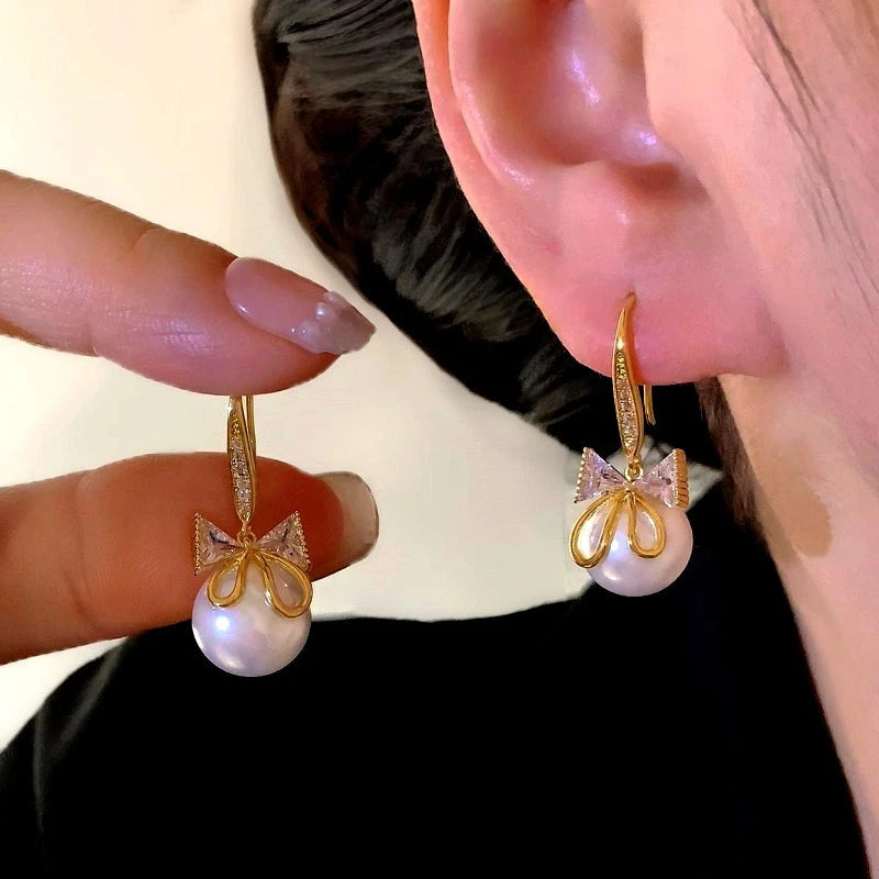 Model showcasing the dangle and style of the 14K Gold-Plated Elegant Zircon Bow Bead Ear Hook Earrings