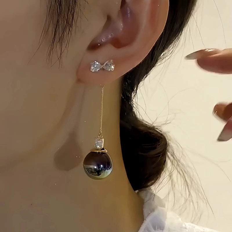 Model showcasing the dangle and style of the 14K Gold-Plated Elegant Zircon Bow Black Pearl Tassel Earrings