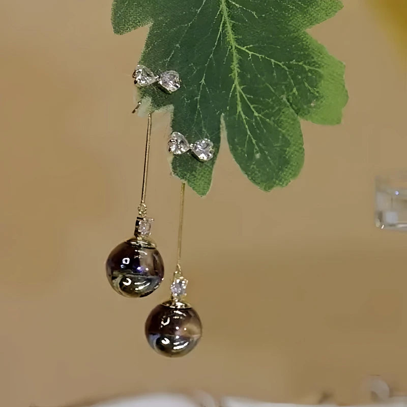 Angled view of the 14K Gold-Plated Elegant Zircon Bow Black Pearl Tassel Earrings