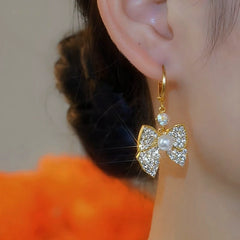 Model showcasing the dangle and style of the 14K Gold-Plated Elegant Zircon Bow Earrings