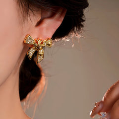 Model showcasing the dangle and style of the 14K Gold-Plated Elegant Zircon Bow Earrings