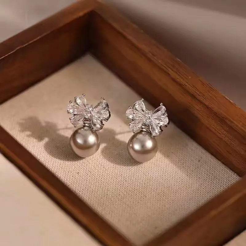 Model showcasing the dangle and style of the 14K Gold-Plated Elegant Zircon Bow Pearl Earrings