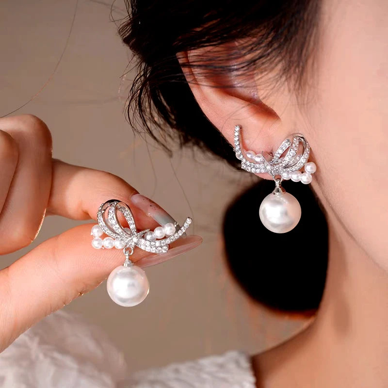 Model showcasing the dangle and style of the 14K Gold-Plated Elegant Zircon Bow Pearl Earrings