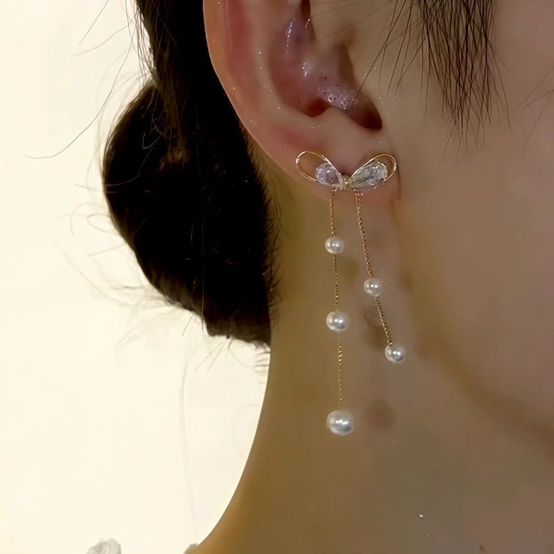 Model showcasing the dangle and style of the 14K Gold-Plated Elegant Zircon Bow Pearl Tassel Earrings