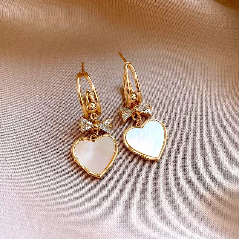 Angled view of the 14K Gold-Plated Elegant Zircon Bow Shell Heart Earrings