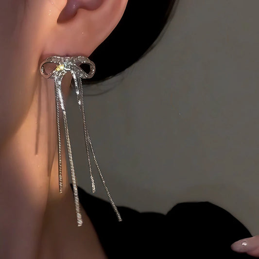 Model showcasing the dangle and style of the 14K Gold-Plated Elegant Zircon Bow Tassel Earrings