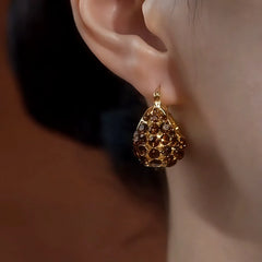 Model showcasing the dangle and style of the 14K Gold-Plated Elegant Zircon Brown Diamond Handbag Earrings