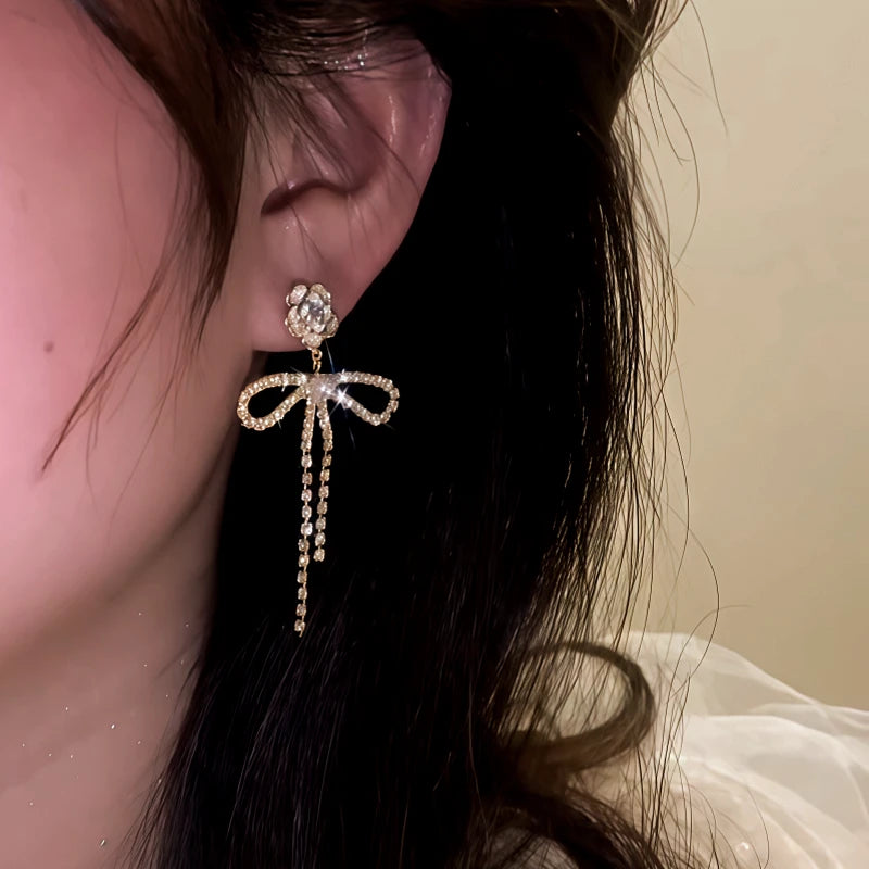 Model showcasing the dangle and style of the 14K Gold-Plated Elegant Zircon Camellia Pearl Bow Earrings
