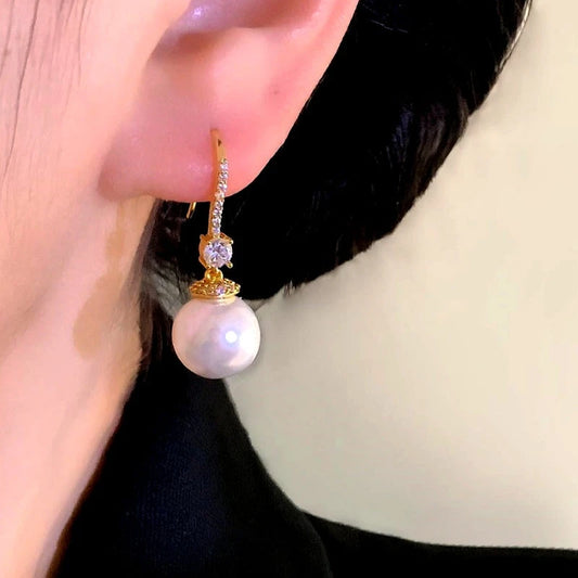 Model showcasing the dangle and style of the 14K Gold-Plated Elegant Zircon Cat's Eye Bead Earrings