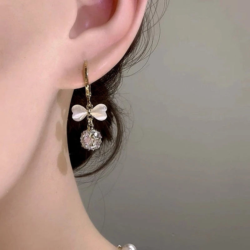 Model showcasing the dangle and style of the 14K Gold-Plated Elegant Zircon Cat's Eye Stone Bow Earrings