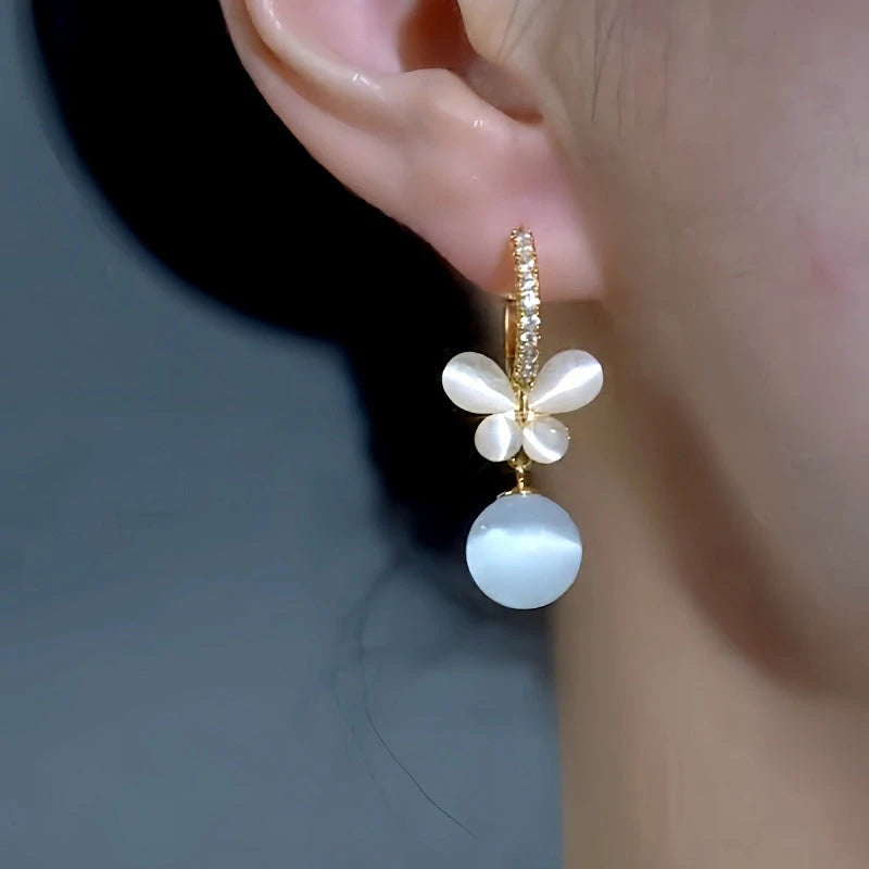 Model showcasing the dangle and style of the 14K Gold-Plated Elegant Zircon Cat's Eye Stone Butterfly Pearl Earrings