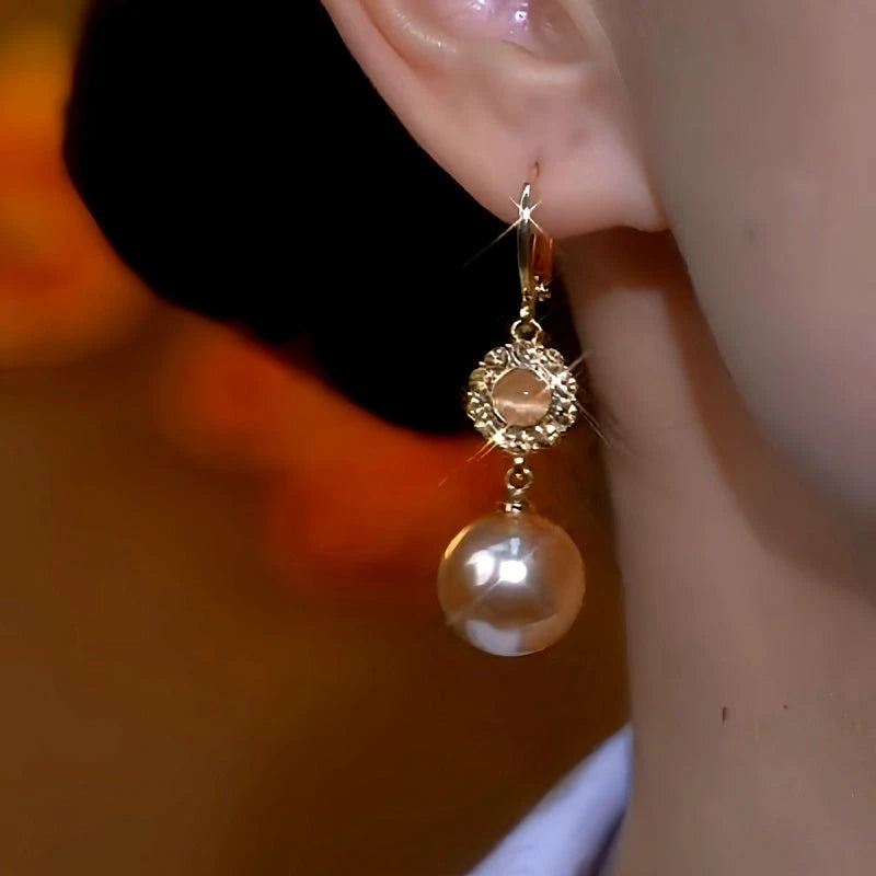 Model showcasing the dangle and style of the 14K Gold-Plated Elegant Zircon Cat's Eye Stone Pearl Earrings